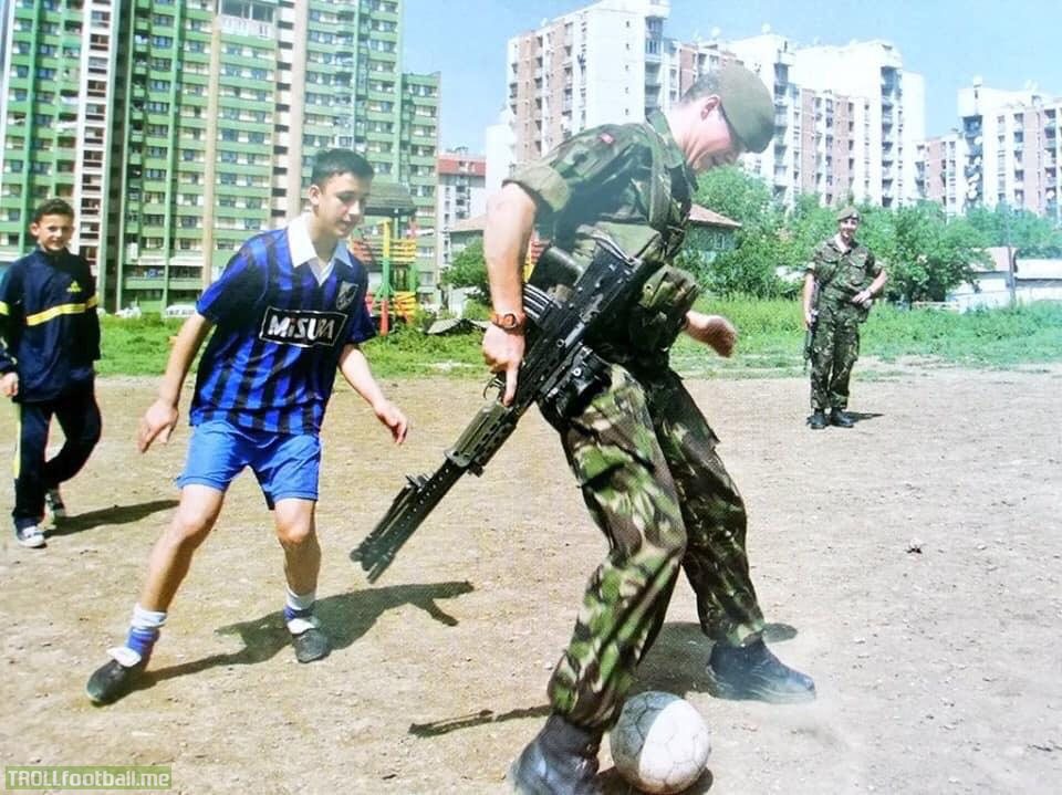1999 Prishtina, Kosovo. A British solider playing football with local kids.